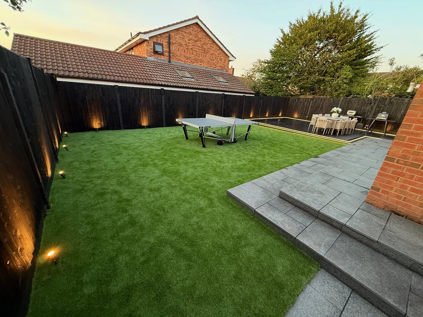 Freshly laid turf lawn with patio and uplit fencing